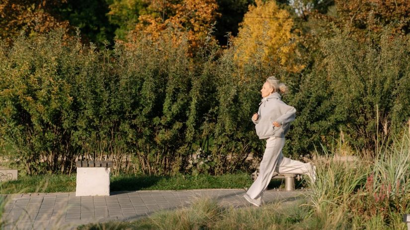 Elderly woman enjoying a healthy jog in a scenic park, showcasing active lifestyle.